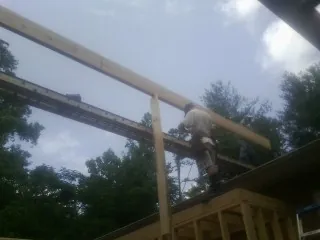 Carpenter setting a ridge beam over a new addition frame — Ice Dam Removal by Roofing Brothers in Katy