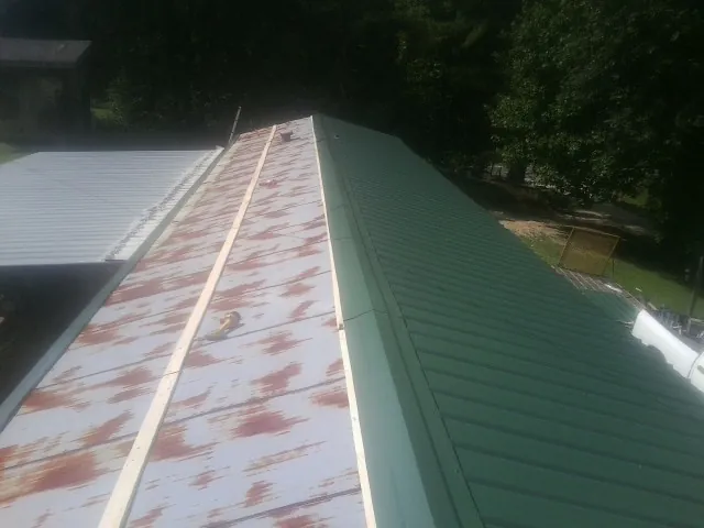 Old rusted panels beside newly installed green metal roofing — Wind Damage Roof Repair by Roofing Brothers in Katy