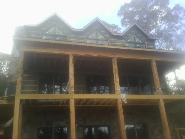 Dormers and porch framing on a large log home under construction — Roof Coating work by our crew in Katy