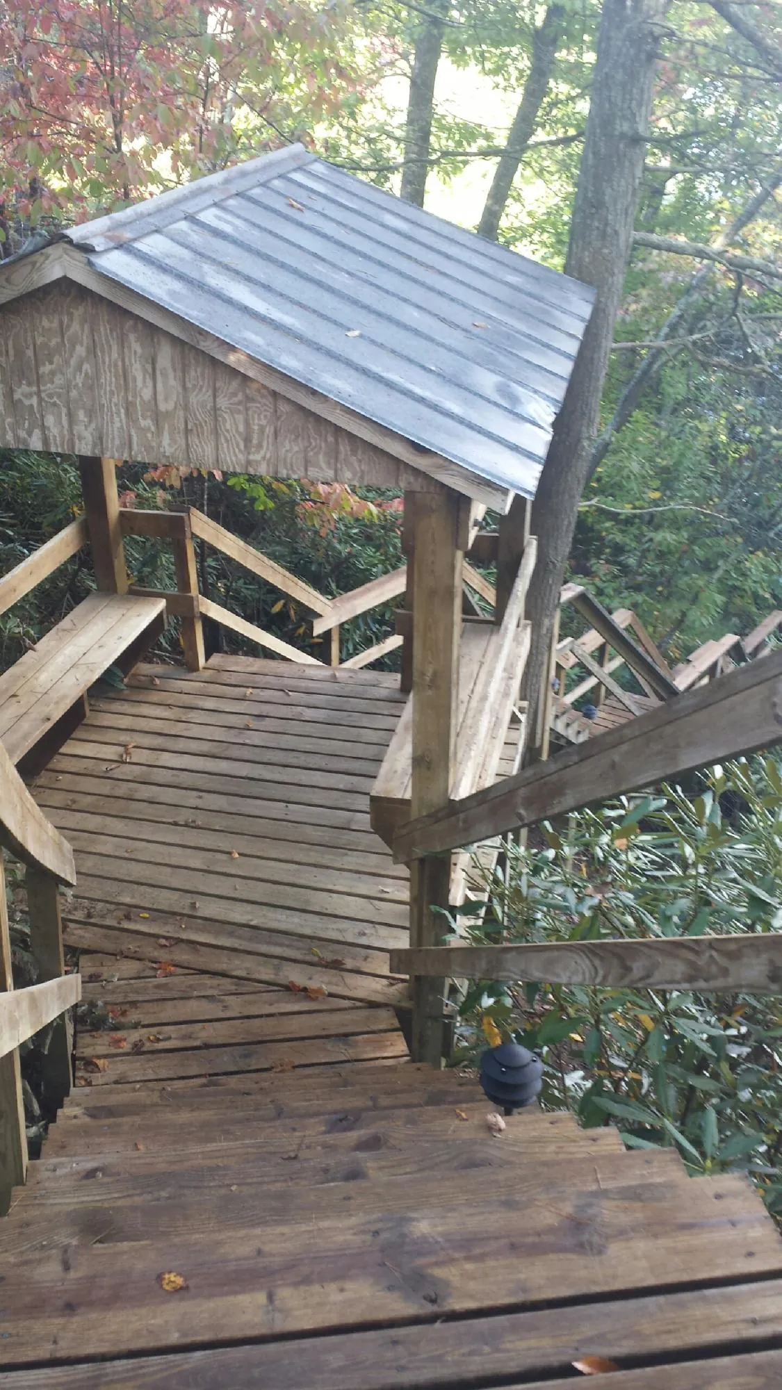 Metal roofed shelter over wooden steps on a wooded walkway — Skylight Repair & Installation work by our crew in Katy