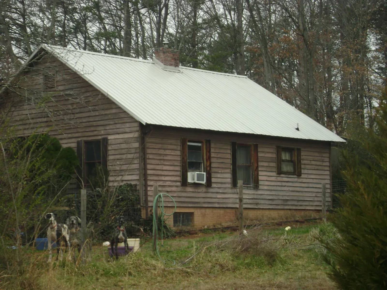 White metal roof on an old wood sided farmhouse, from a Metal Roof Installation job in Katy