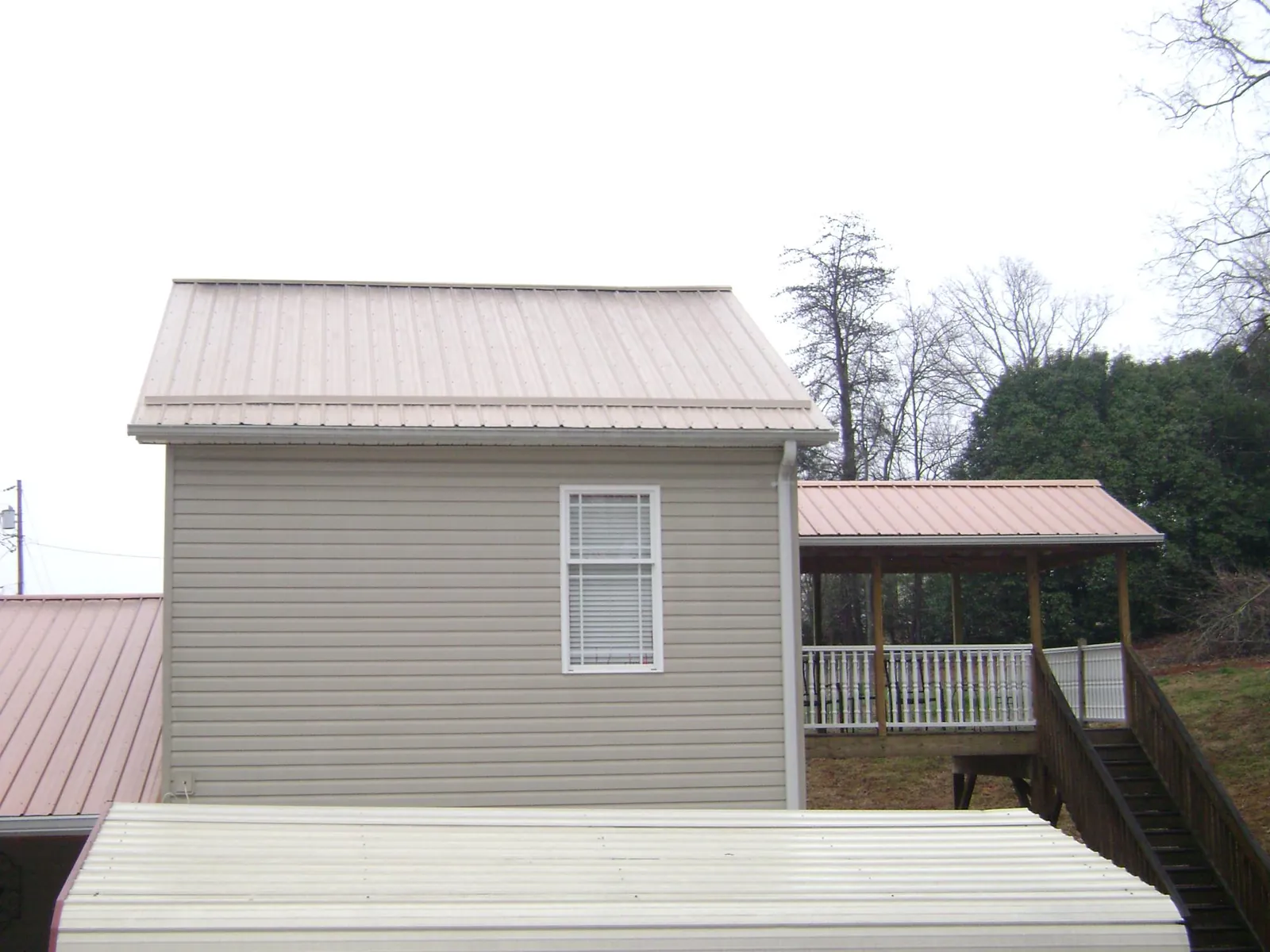 Tan metal roofs on a two story addition and attached porch, from a Roof Replacement job in Katy