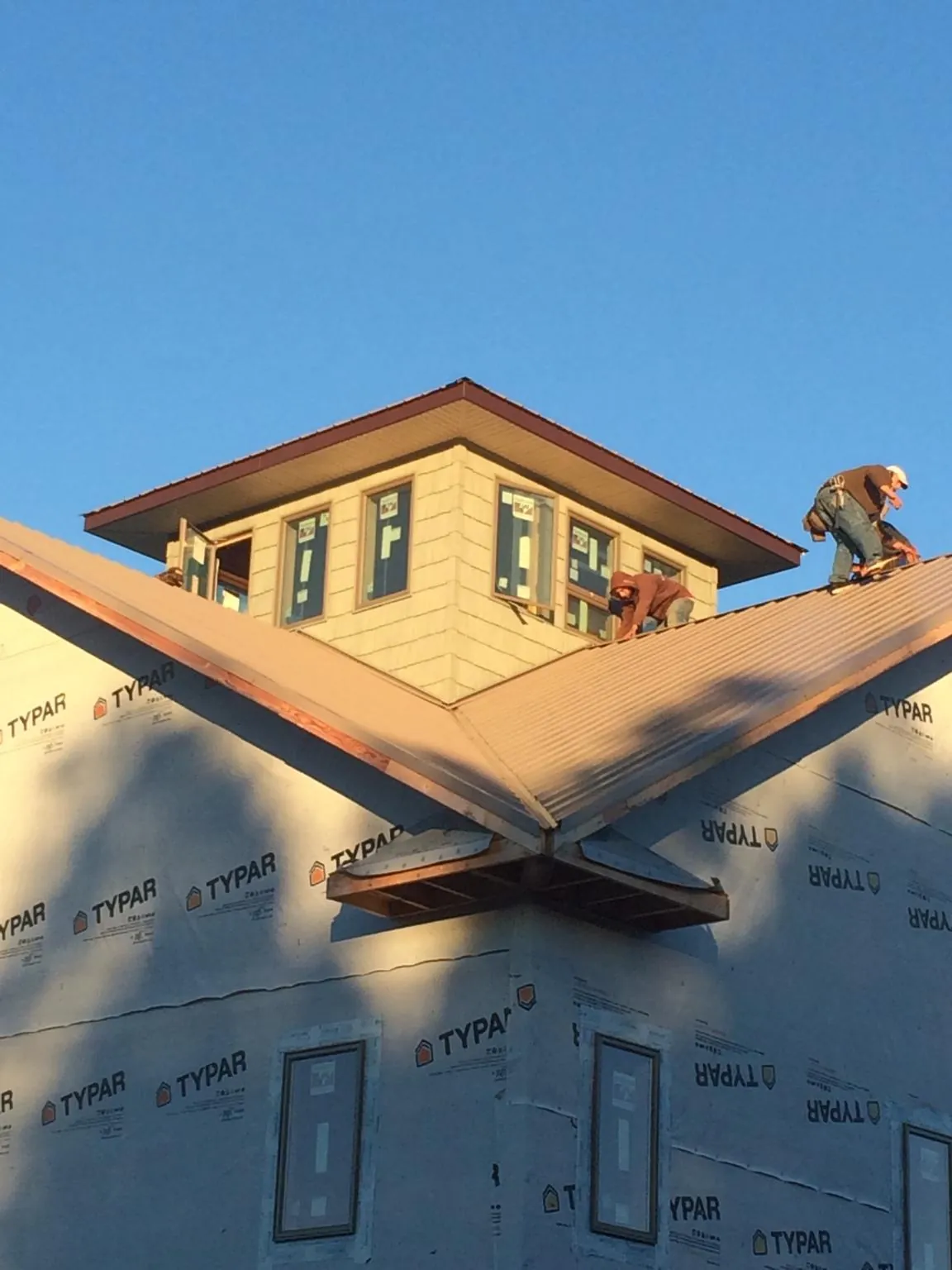 Roofers working around a rooftop cupola on a new metal roof at sunset — Roof Waterproofing in Katy by Roofing Brothers